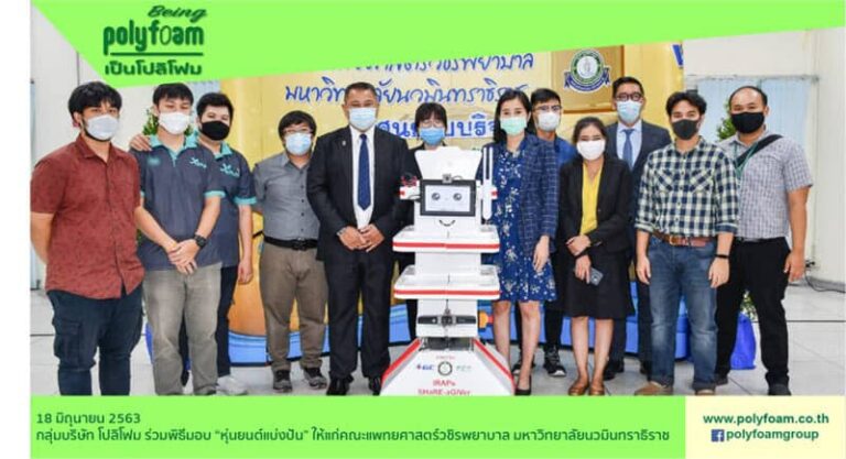 กลุ่มคนสวมหน้ากากอนามัยยืนถ่ายรูปกับหุ่นยนต์ช่วยเหลือทางการแพทย์ในพิธีมอบ